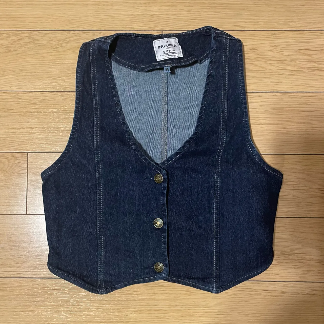 Chaleco de jean de Inquieta, talle M, color azul oscuro, con botones dorados y espalda semiabierta. Es una prenda moderna y a estrenar, ideal para un look canchero, moderno y versátil, pudiendo formar parte de un oufit casual de día, o de una salida de noche.