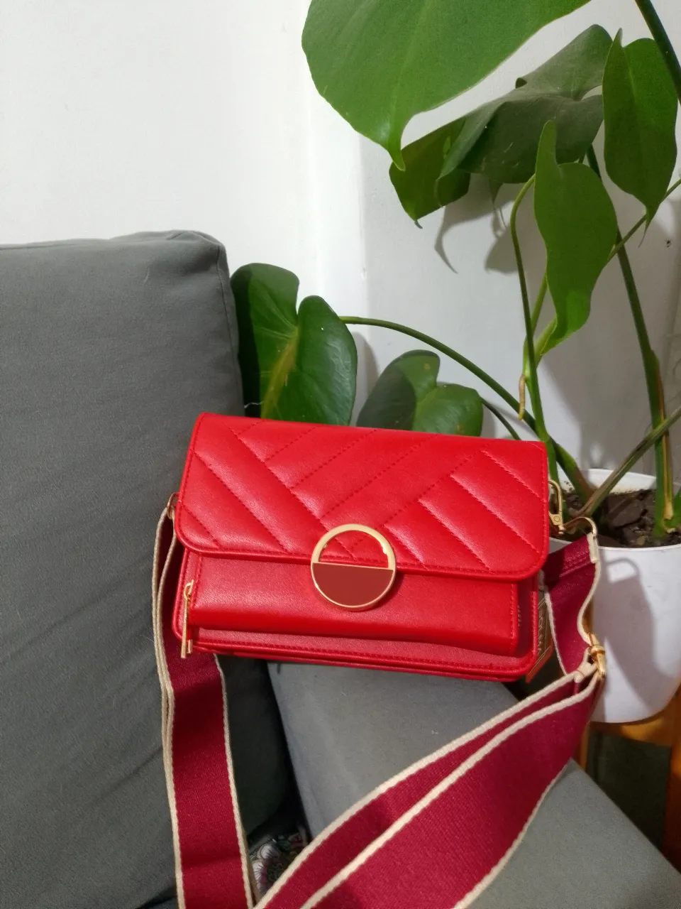 Cartera bandolera roja con diseño acolchado y detalle dorado. Ideal para un look moderno y elegante.