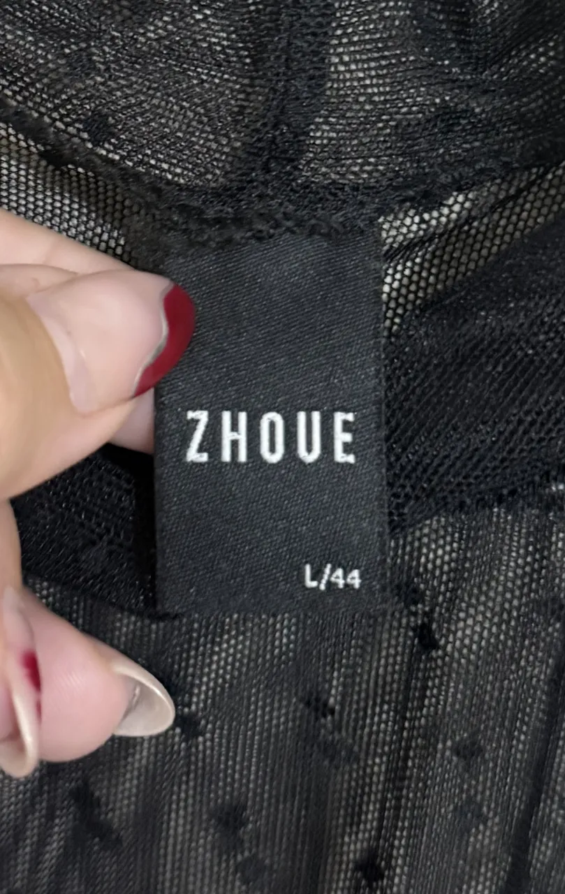 Remera negra de manga larga con cuello alto y textura de lunares pequeños. La tela es transparente.