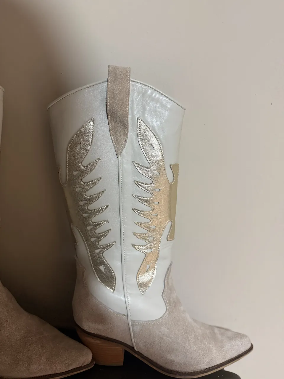 Botas de caña alta, color blanco con detalles plateados y gamuza beige. Cierre lateral.