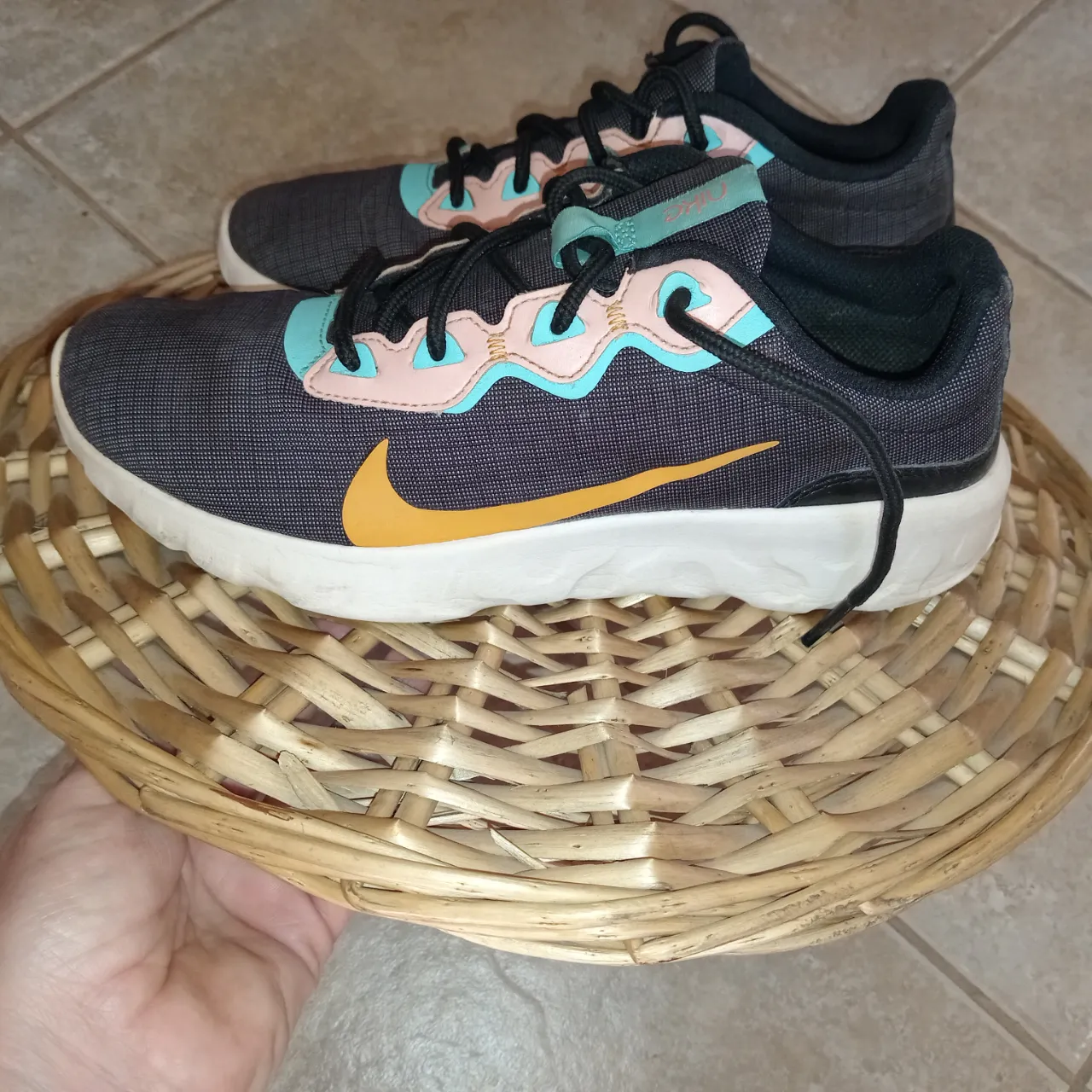 Zapatillas deportivas Nike con detalles en rosa y celeste. Cordones negros y suela blanca.La pipa de Nike amarilla.