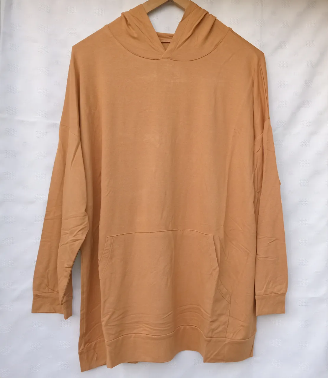 Buzo con capucha y bolsillo canguro delantero. Manga larga.El color es entre naranja y caqui.