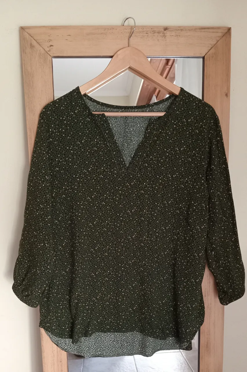 Remera verde oscuro con estampa de pequeños puntos blancos y verdes. Tiene mangas 3/4 y escote en V.Mide 45 de hombro, 57 de sisa, 71 largo de atrás, 67 largo de adelante. 