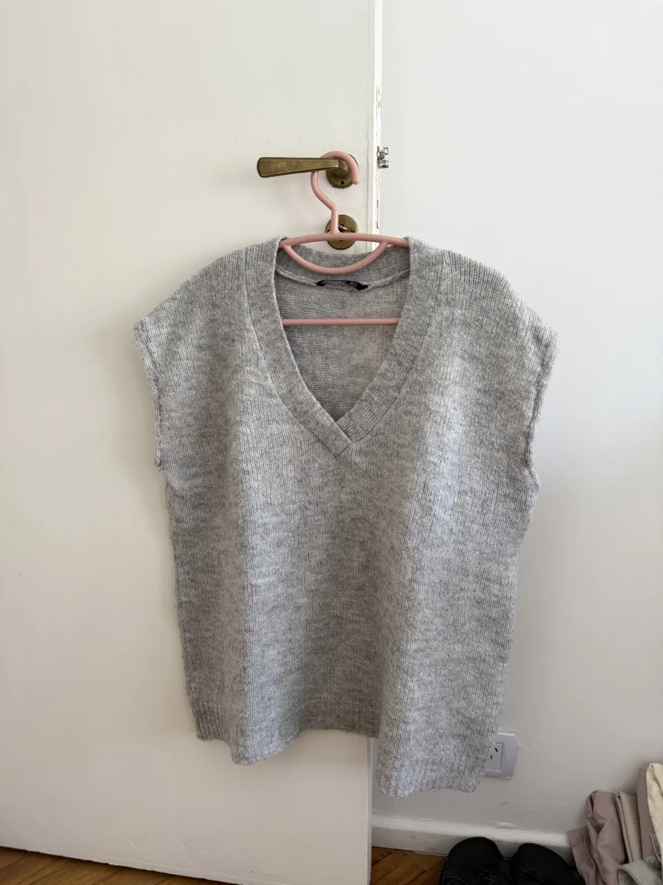 Sweater chaleco de tejido gris con cuello en V y sin mangas. Tipo oversize 