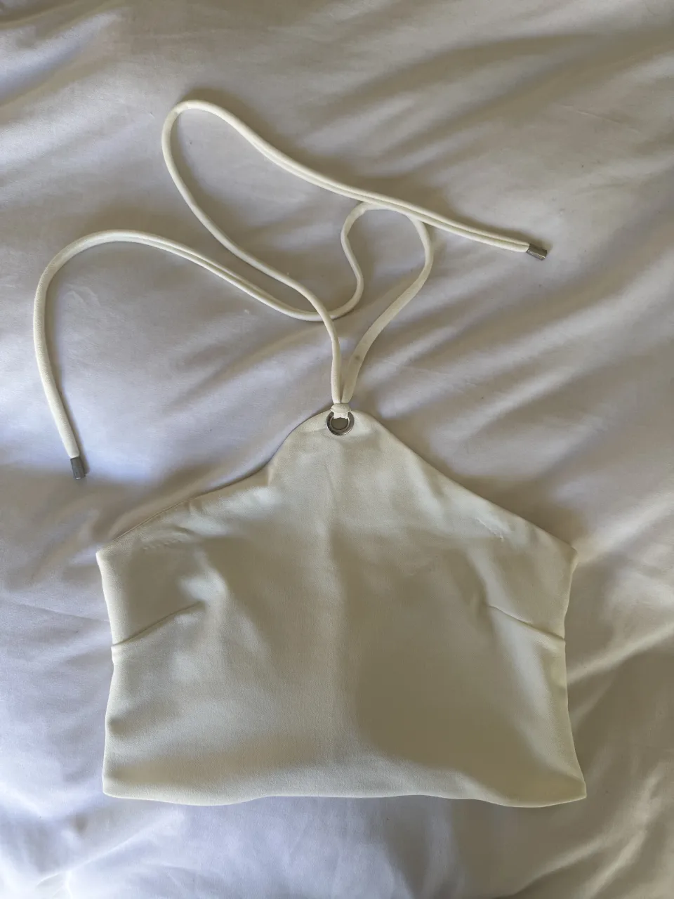 Top blanco con tiras para atar en el cuello y espalda. Posee un cierre en la parte trasera.