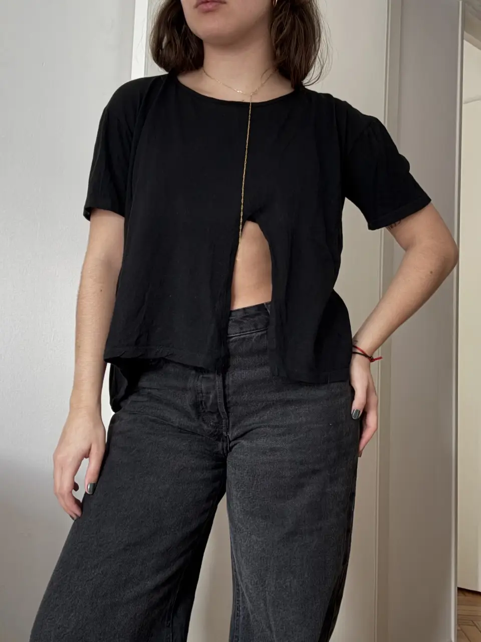 Remera negra con abertura frontal. Corte recto y mangas cortas. Ideal para un look casual y moderno.