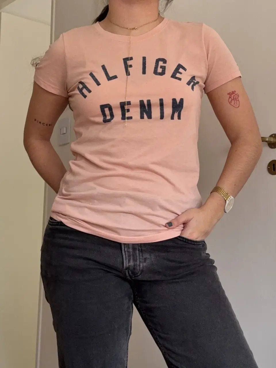 Remera Hilfiger Denim de mujer, color rosa, con estampado delantero. Talle M. Ideal para un look casual y cómodo. Tiene una pequeña mancha al lado del logo