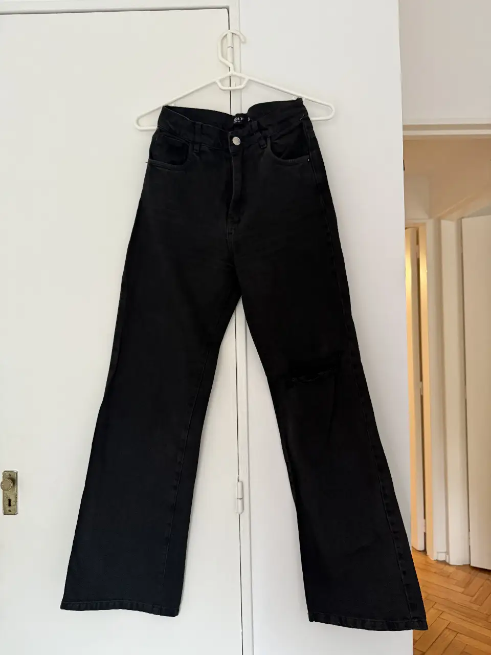 Jeans negro de tiro alto Wide Leg, con rotura en la rodilla. Talle 34, de la marca Holy Jeans. Ideal para un look casual y moderno. Medidas: cintura 30cm, cadera 36cm, entrepierna 74cm, muslo 23 cm y ancho de bota 21cm 