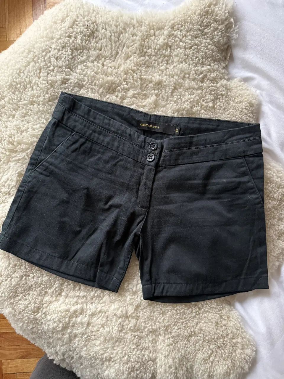 Short de mujer negro, tiro alto, con dos botones en la cintura y bolsillos traseros. Ideal para un look casual y versátil.