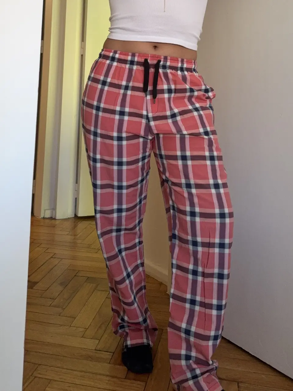 Pantalón de pijama de hombre o mujer, con estampado a cuadros en tonos rojos y blancos. Tiene cintura elastizada con cordón negro y un bolsillo trasero con el logo de la marca. Talle S.