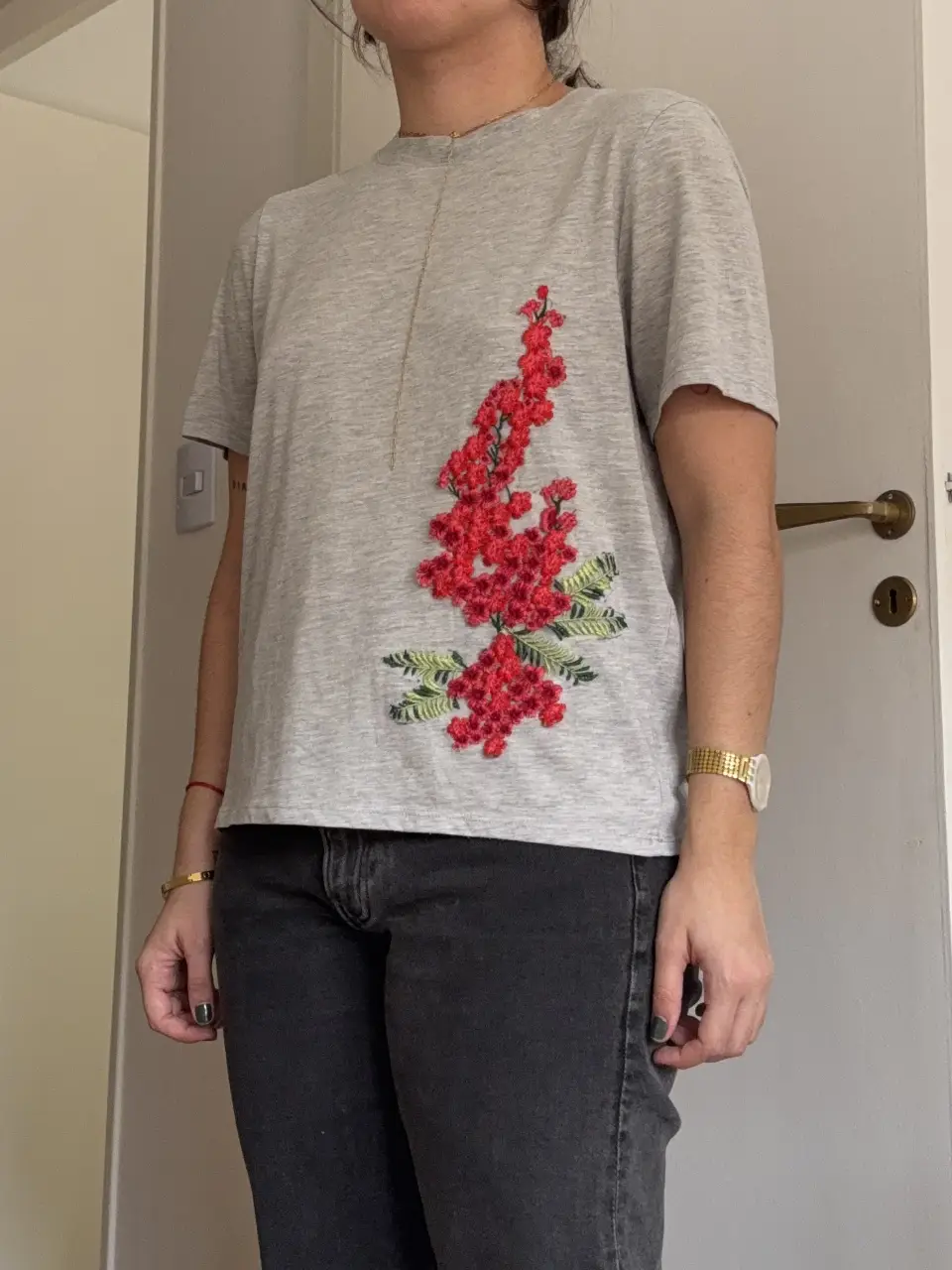 Remera gris de mujer con bordado floral en el frente. Talle S. Ideal para un look casual y cómodo.