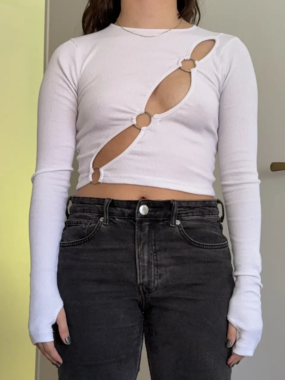 Top manga larga blanco con aberturas y detalles de anillos metálicos. Ideal para un look moderno y audaz.