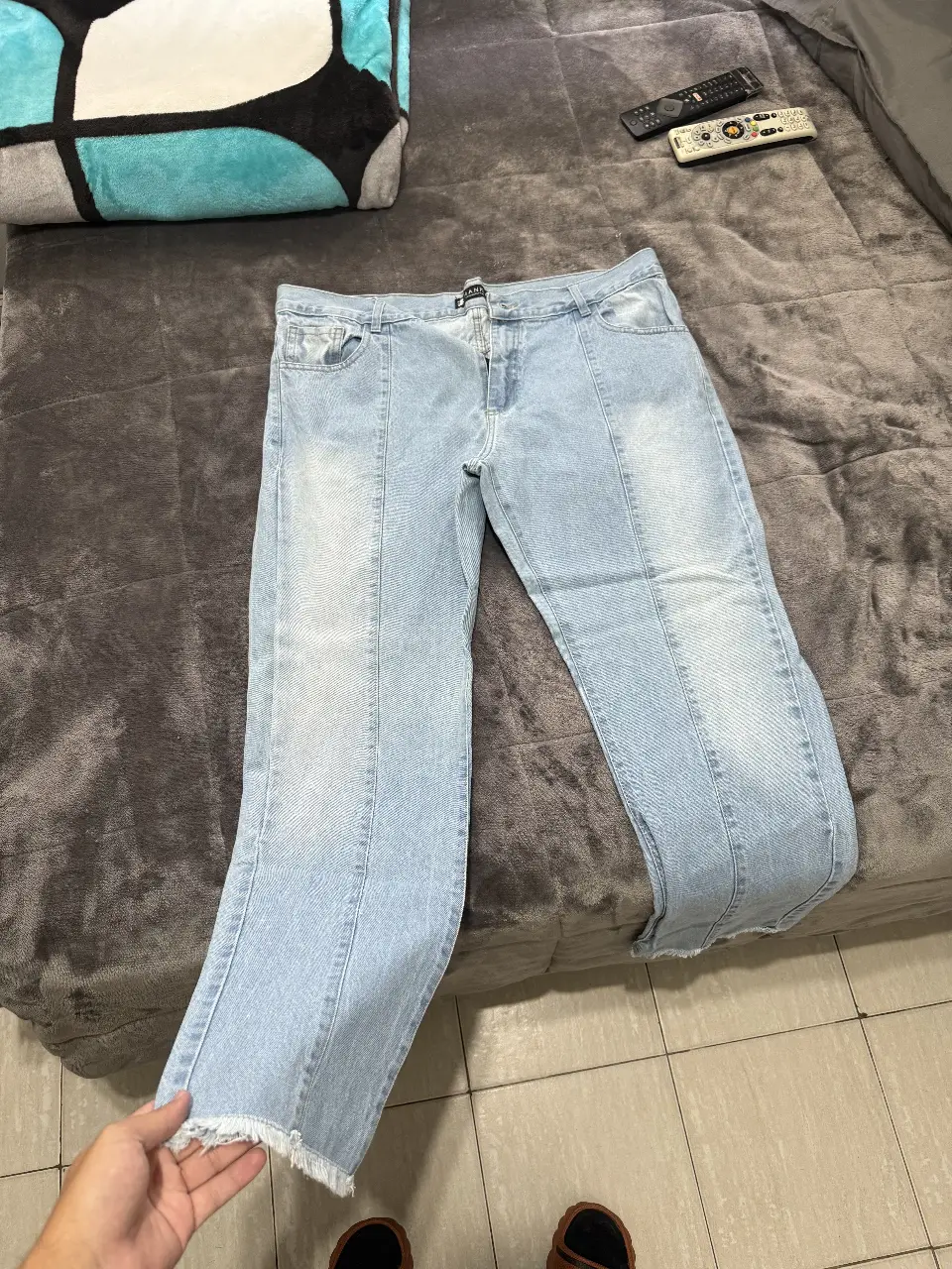 Jeans rectos de hombre, celeste claro, con detalles de costura y corte en el borde inferior. Talle 40, de la marca Manki.