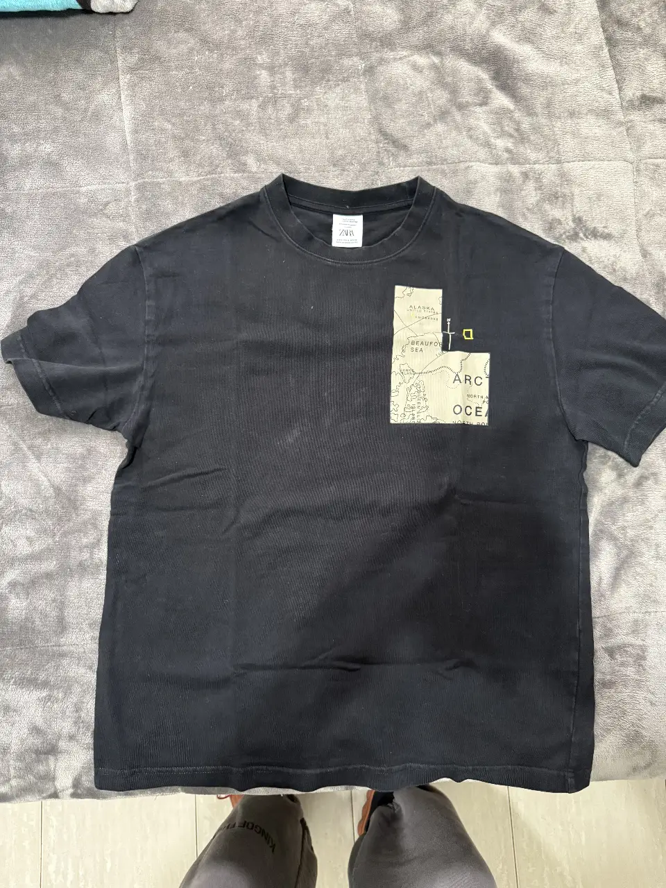 Remera negra de hombre de la marca Zara con estampado de National Geographic en la espalda. Talle S. Ideal para un look casual y cómodo.