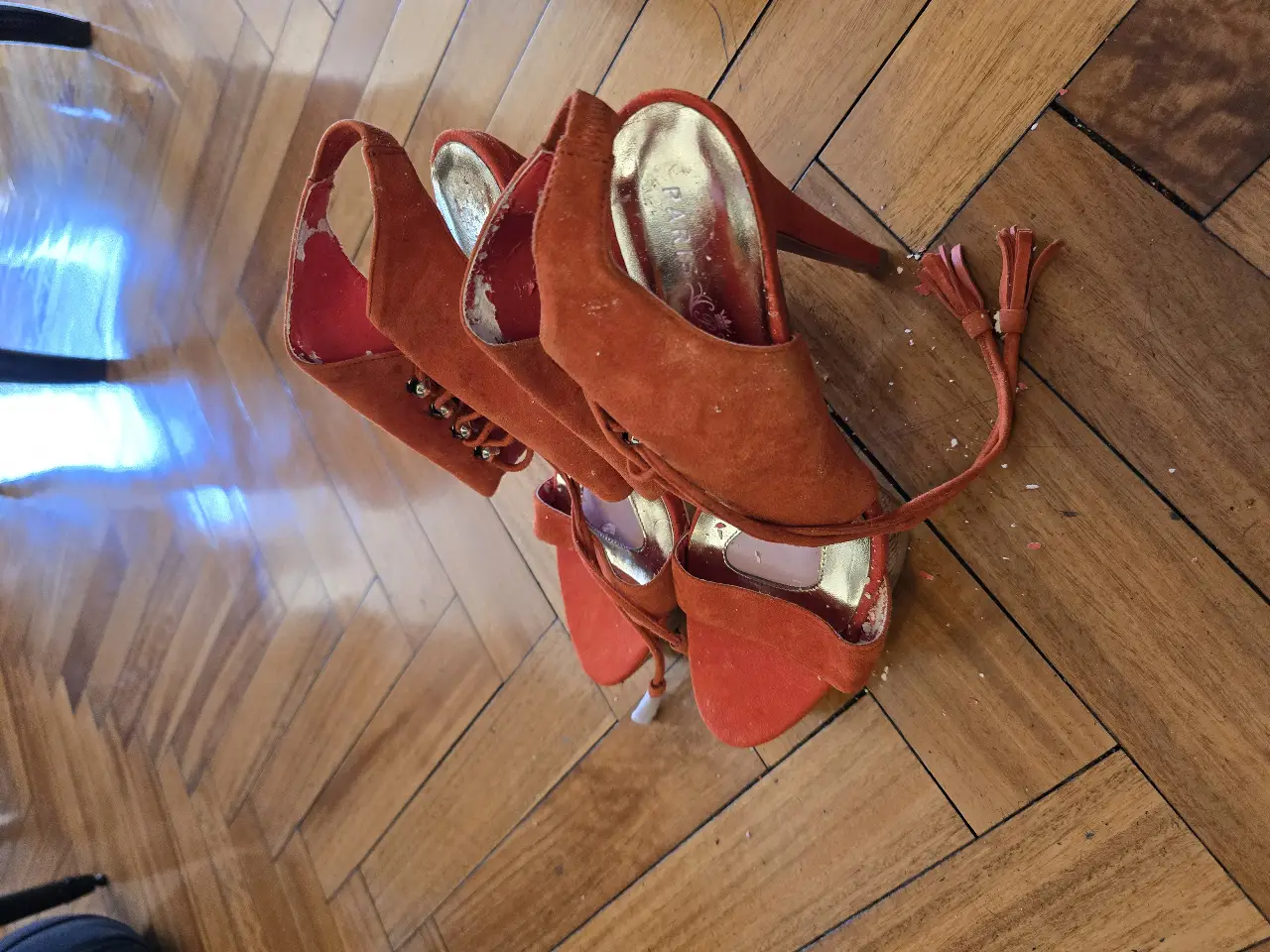 Sandalias de taco alto color naranja, con detalles de gamuza y tiras para atar al tobillo. Ideales para darle un toque de color y sofisticación a cualquier look de fiesta.
