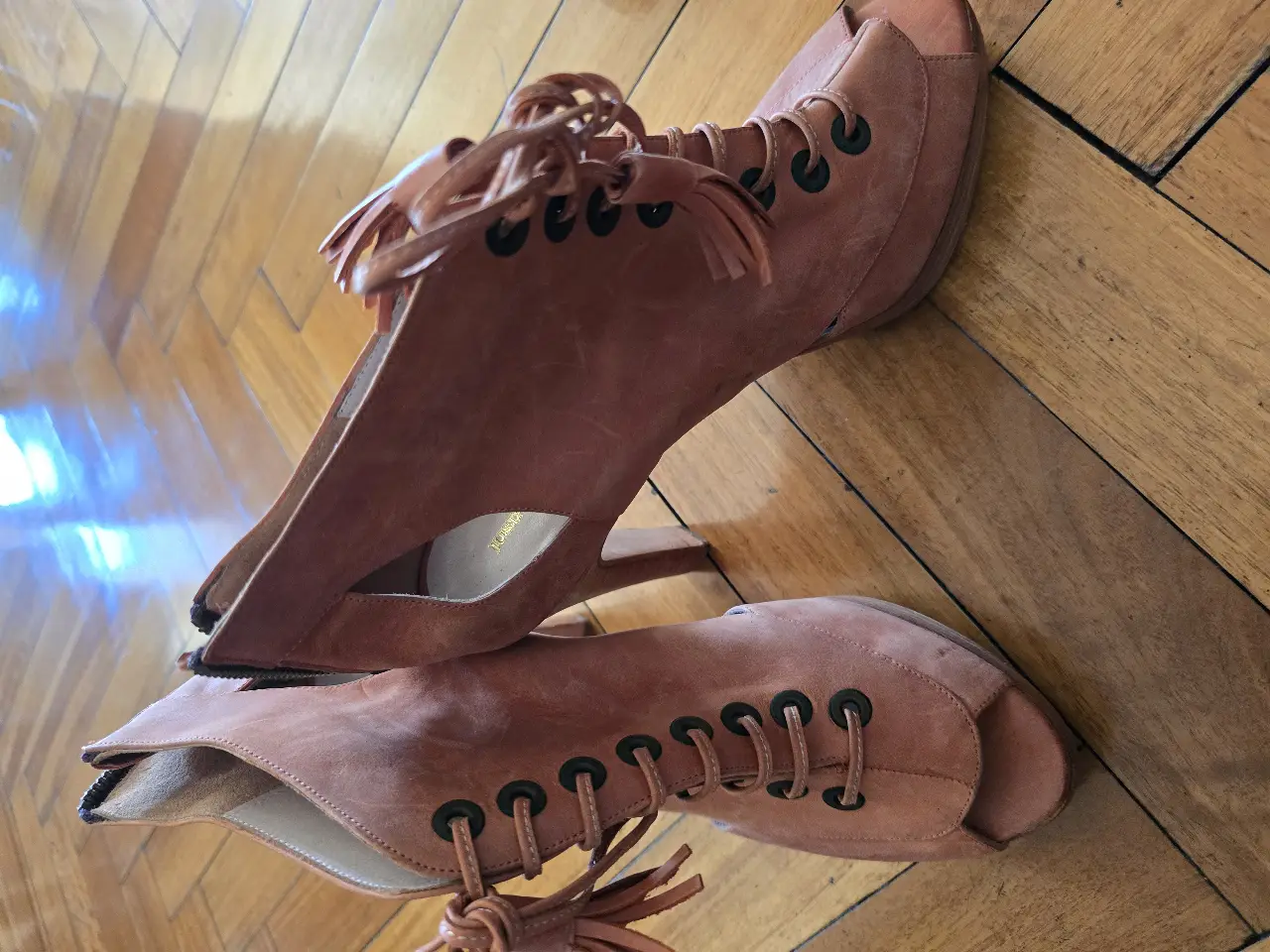 Sandalias de taco alto color marrón, con detalles de cordones y flecos. Ideales para un look de fiesta o salida.
