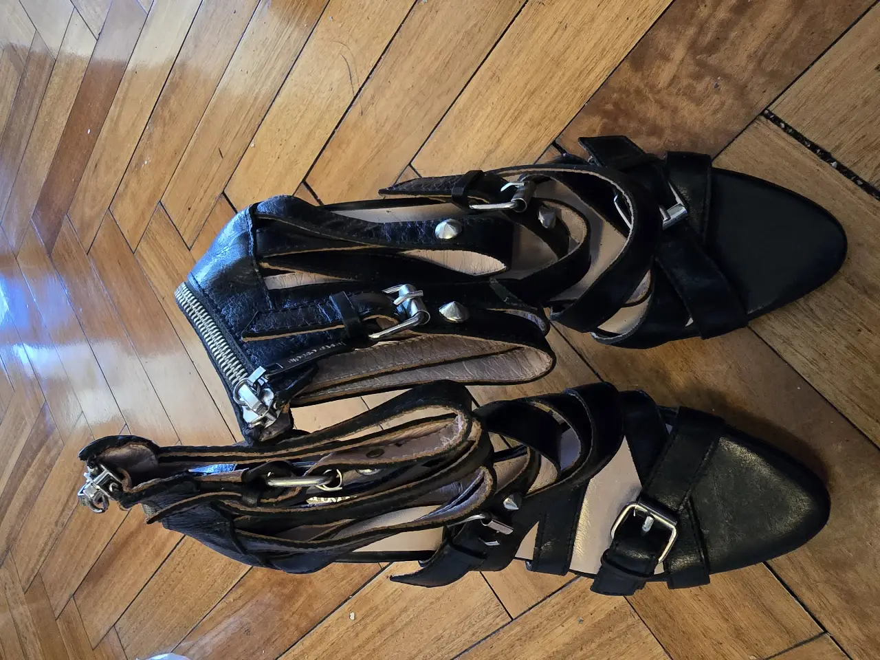 Sandalias de taco alto negras con cierre en el talón y detalles de hebillas. Ideales para un look de fiesta o salida.