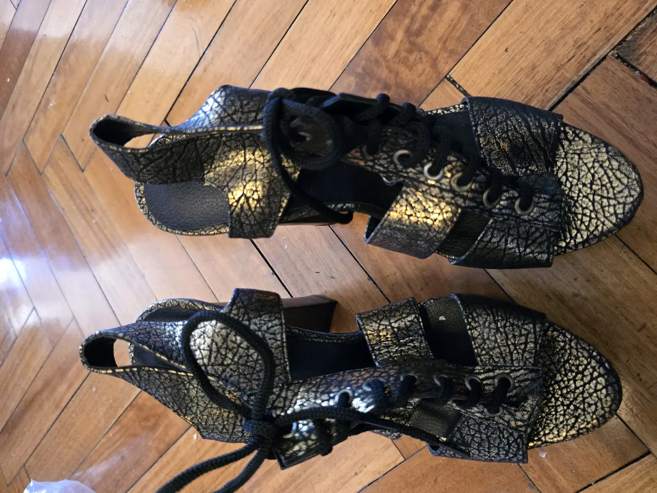 Sandalias de taco alto con diseño texturado en negro y detalles dorados. Ideales para eventos y fiestas.