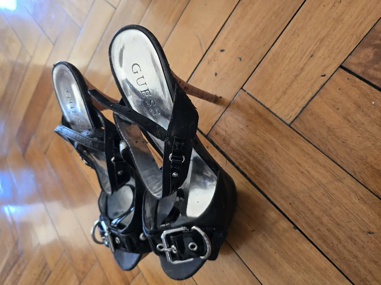 Sandalias Guess negras con detalles plateados y taco alto. Ideales para fiestas y eventos.