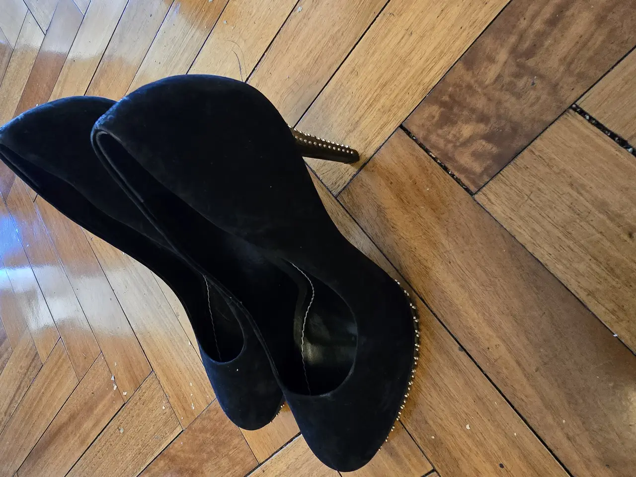 Zapatos de taco alto negros de gamuza con detalles dorados en el taco. Ideales para fiestas y eventos especiales.