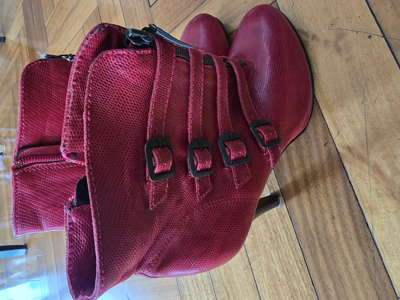 Botas rojas de cuero con taco alto y detalles de hebillas. Ideales para darle un toque audaz a cualquier look. Perfectas para salir y destacar.