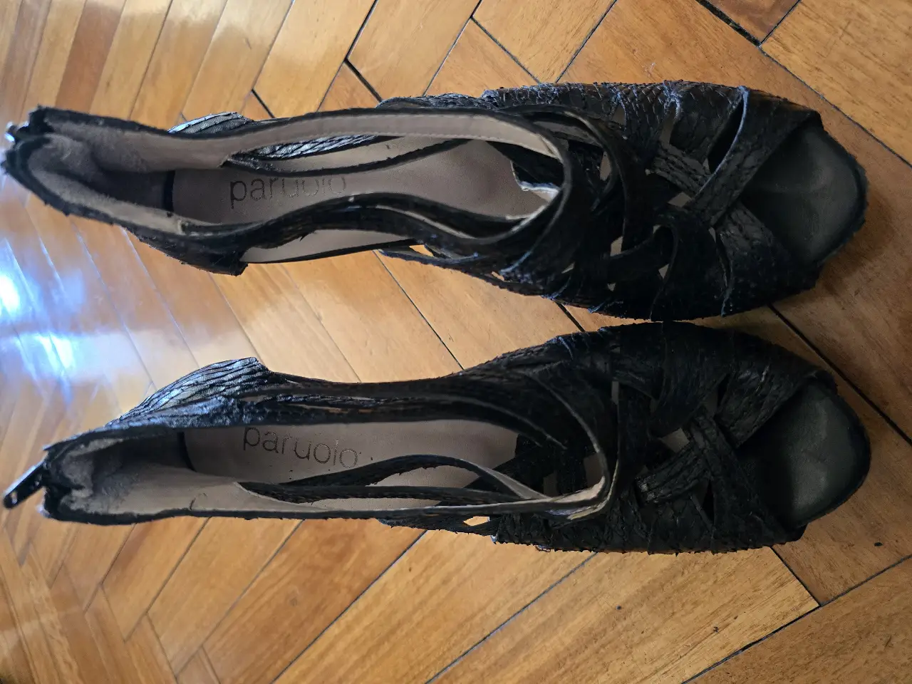 Sandalias negras de cuero con diseño calado y detalles trenzados. Ideales para un look elegante y sofisticado.