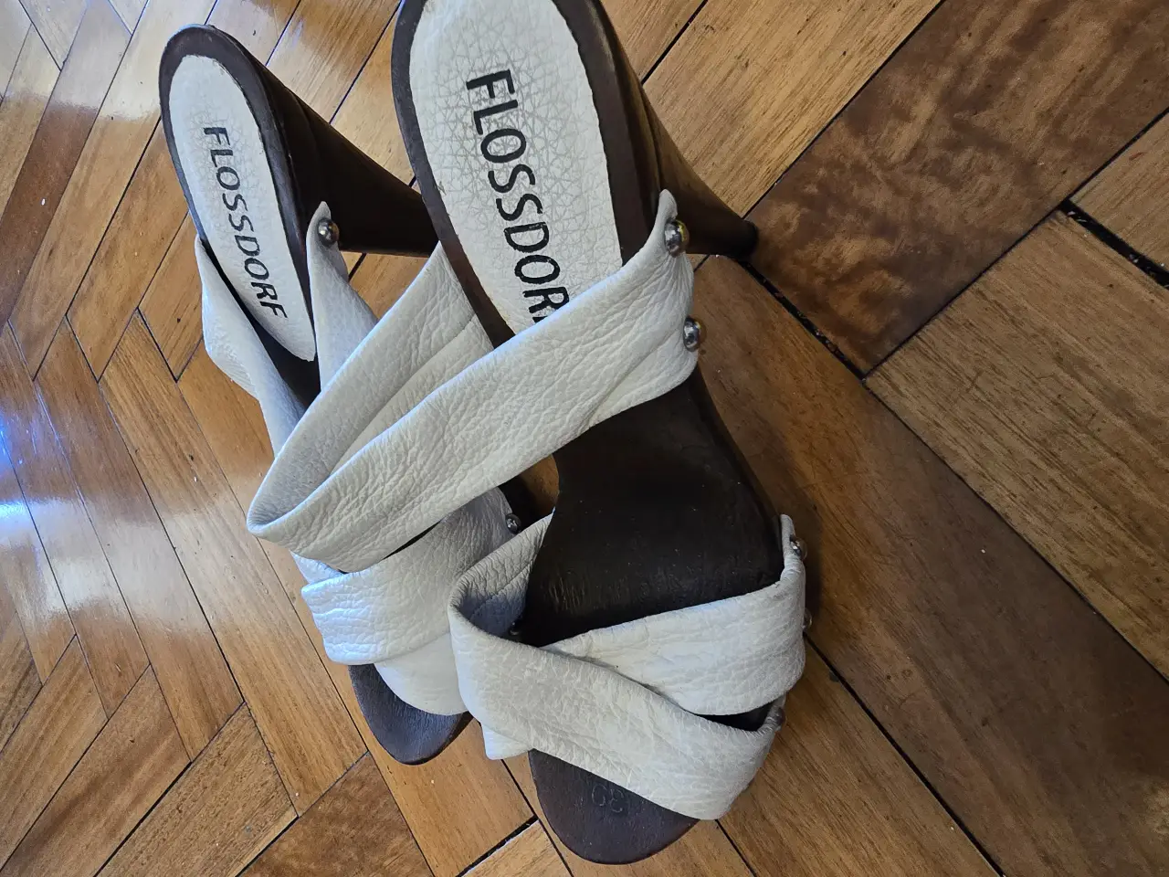 Sandalias de mujer Flossdorf, con taco cónico y tiras cruzadas de cuero blanco. Ideales para un look elegante y cómodo.
