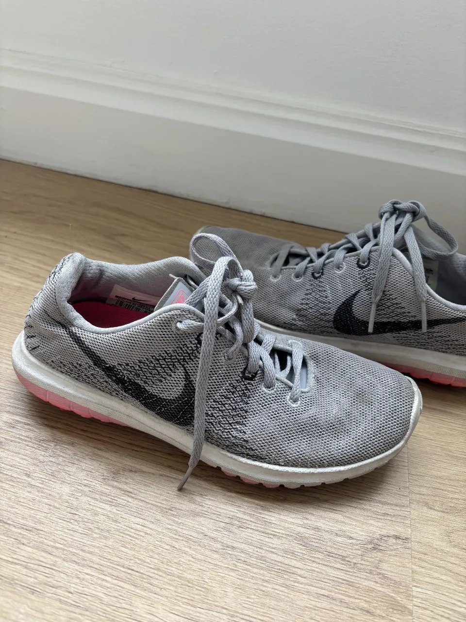 Zapatillas Nike grises con detalles en negro y suela rosa. Ideales para running y entrenamiento.
