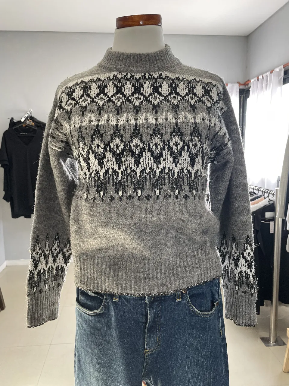 Sweater de lana gris con diseño geométrico en blanco y negro. Cuello alto y mangas largas. Ideal para un look casual y abrigado.