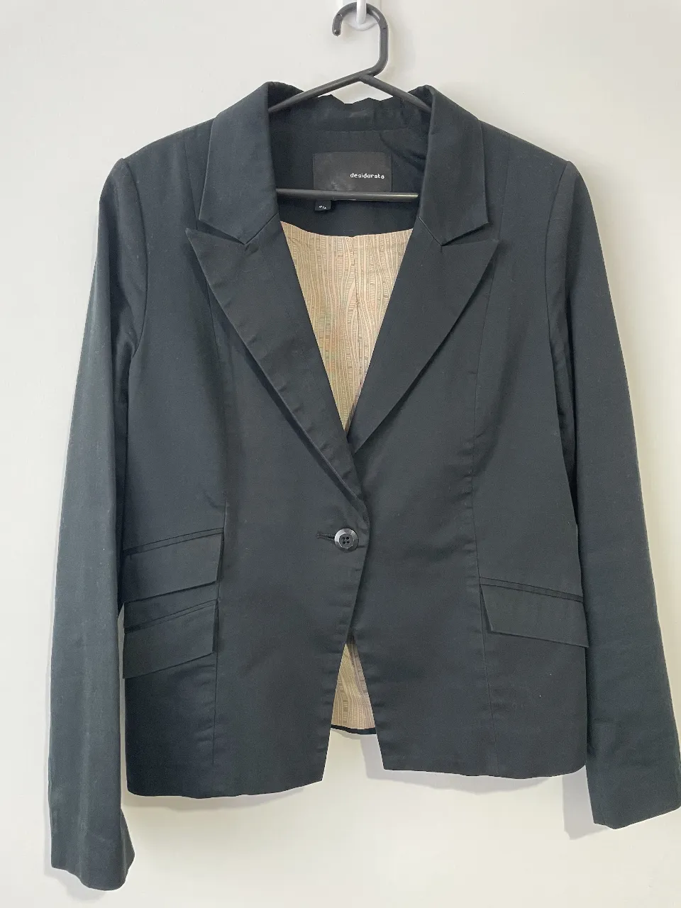 Blazer negro de mujer, entallado, con un botón y bolsillos delanteros. Ideal para un look formal o de trabajo. Marca Desiderata.