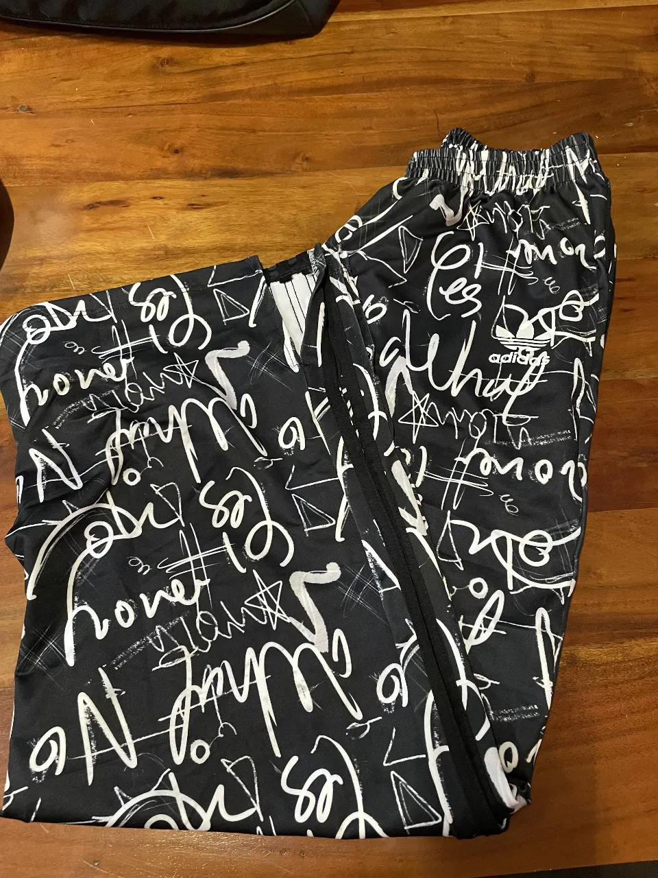 Pantalón suelto de mujer, con estampado de letras blancas sobre fondo negro. Ideal para un look casual y moderno. Confeccionado en tela liviana y cómoda, perfecto para el día a día.