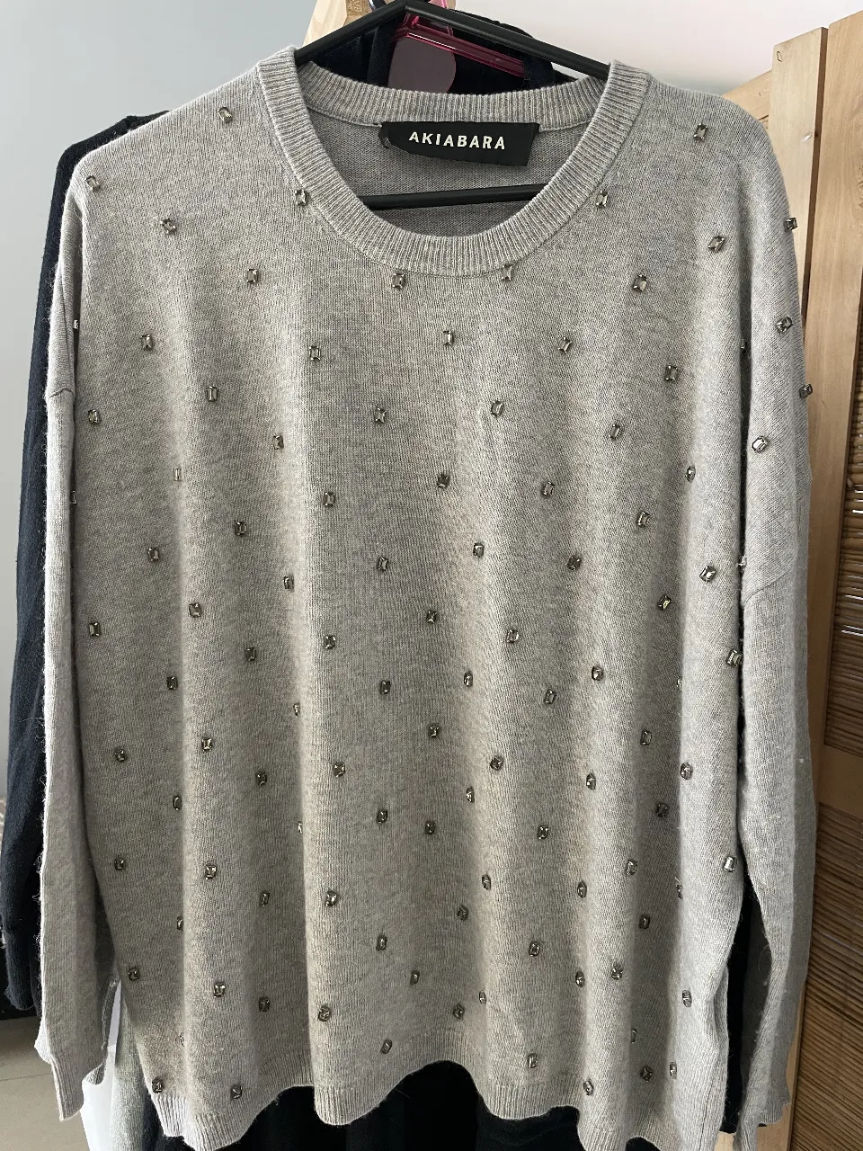 Sweater gris de mujer con detalles de strass. Cuello redondo y manga larga. Ideal para un look elegante y moderno.