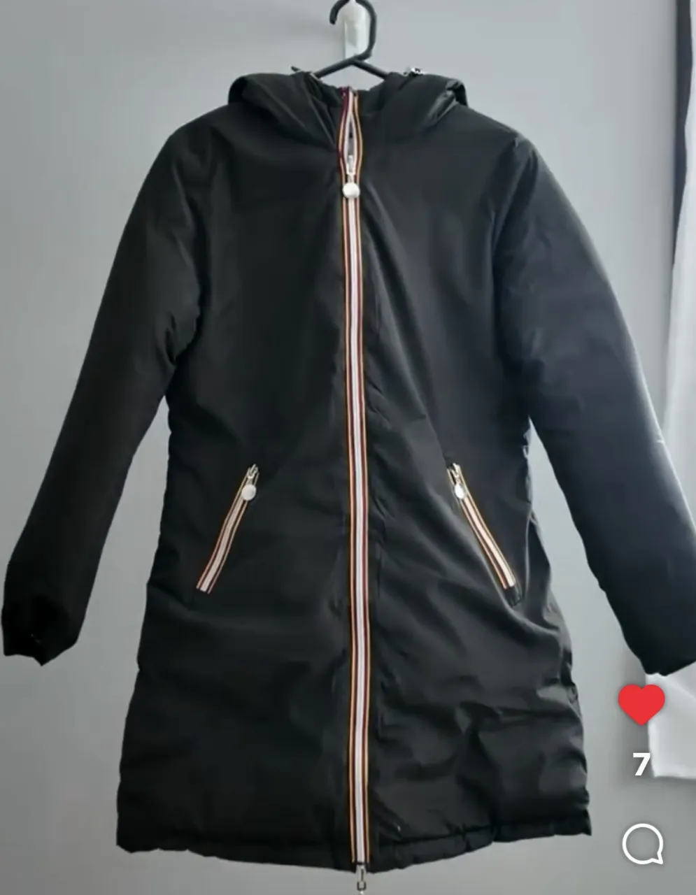 Campera larga de abrigo para mujer, color negro. Ideal para el invierno, con capucha y cierre frontal. Posee bolsillos con cierre y detalles en blanco y rojo en el cierre. Perfecta para un look casual y abrigado.