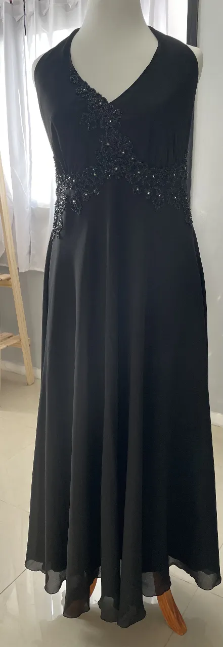 Vestido largo de fiesta negro, con detalles de pedrería en la parte superior. Corte en A, ideal para eventos formales.