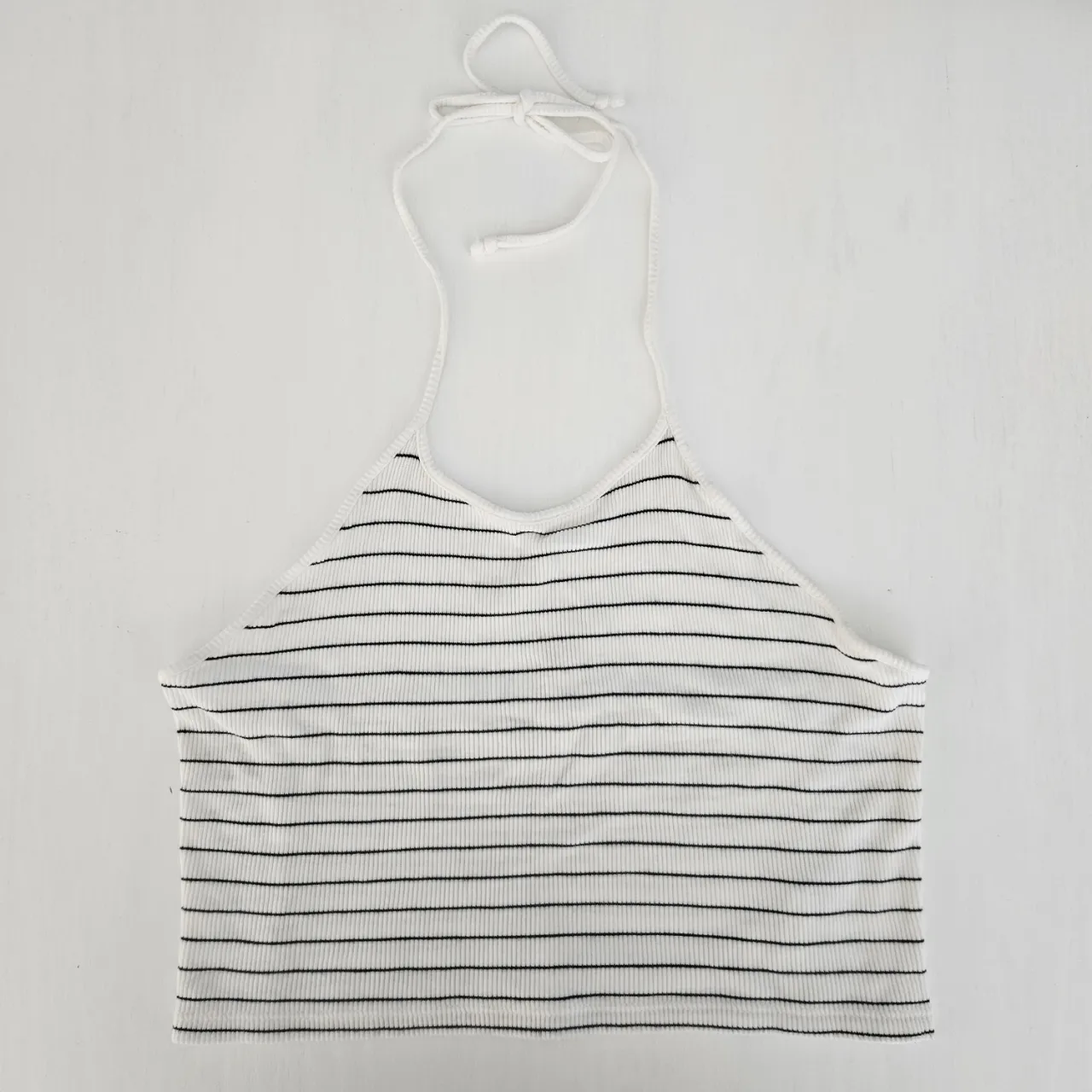 Top a rayas blancas y negras, con breteles finos que se atan en la nuca. La espalda es semi descubierta.