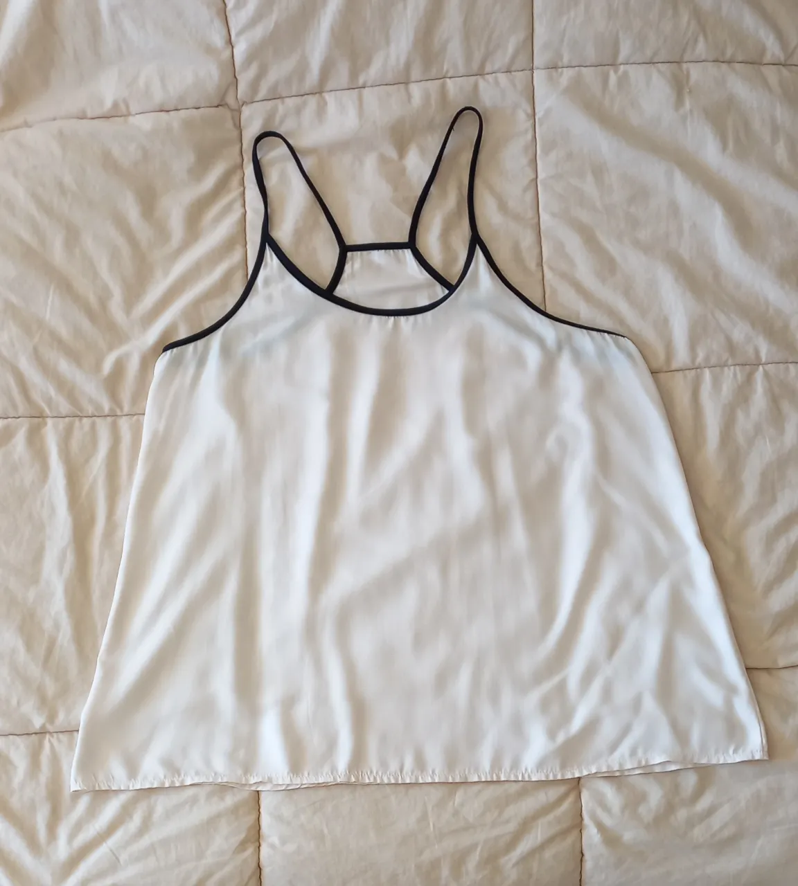 Top blanco con detalles en negro, ideal para un look casual y fresco. Perfecto para combinar con jeans o shorts.