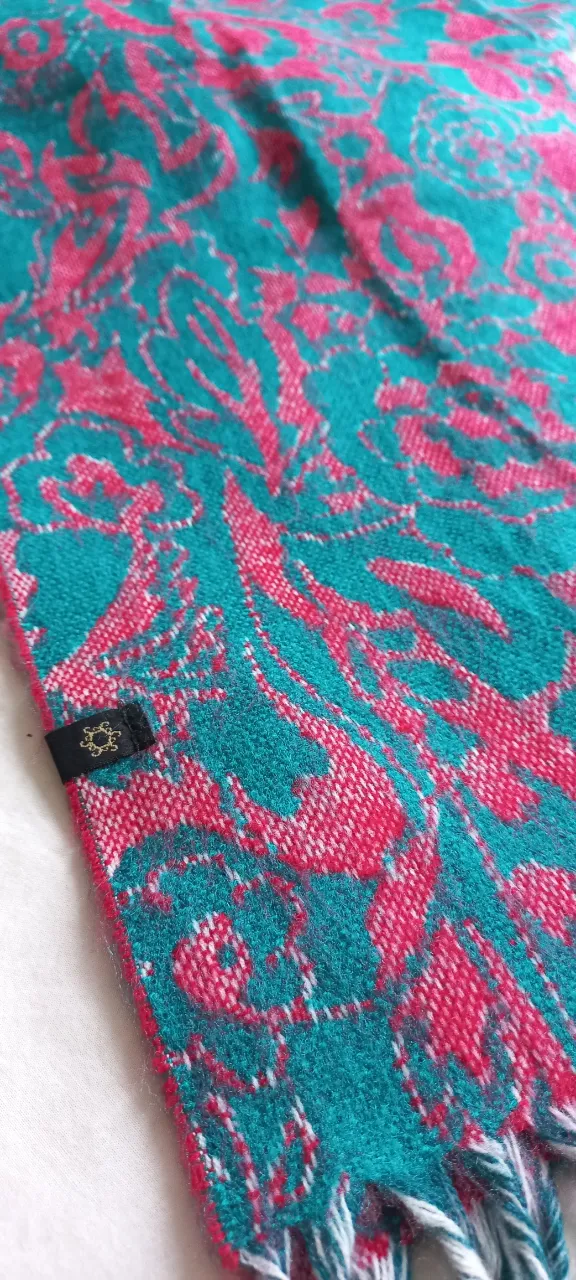 Bufanda tejida con un hermoso diseño floral en tonos vibrantes de verde y rojo. Perfecta para darle un toque de color y estilo a cualquier outfit.