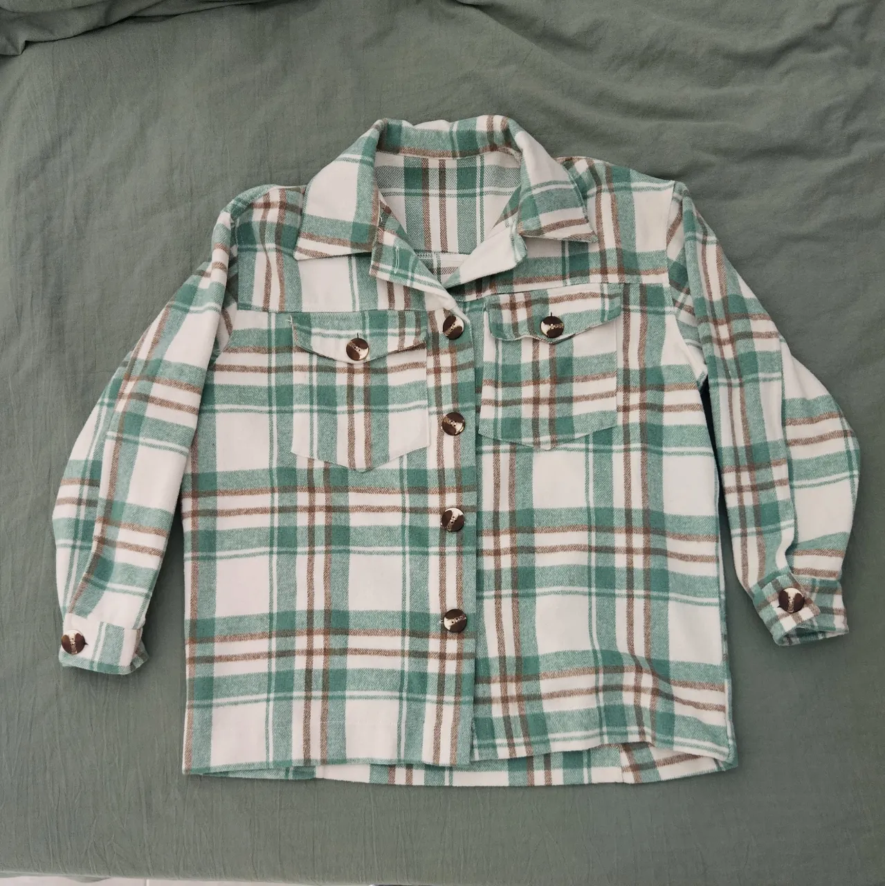 Camisa tipo de paño a cuadros, ideal para un look casual y cómodo. Perfecta para usar abierta sobre una remera o cerrada. Posee botones al frente y en los puños.
