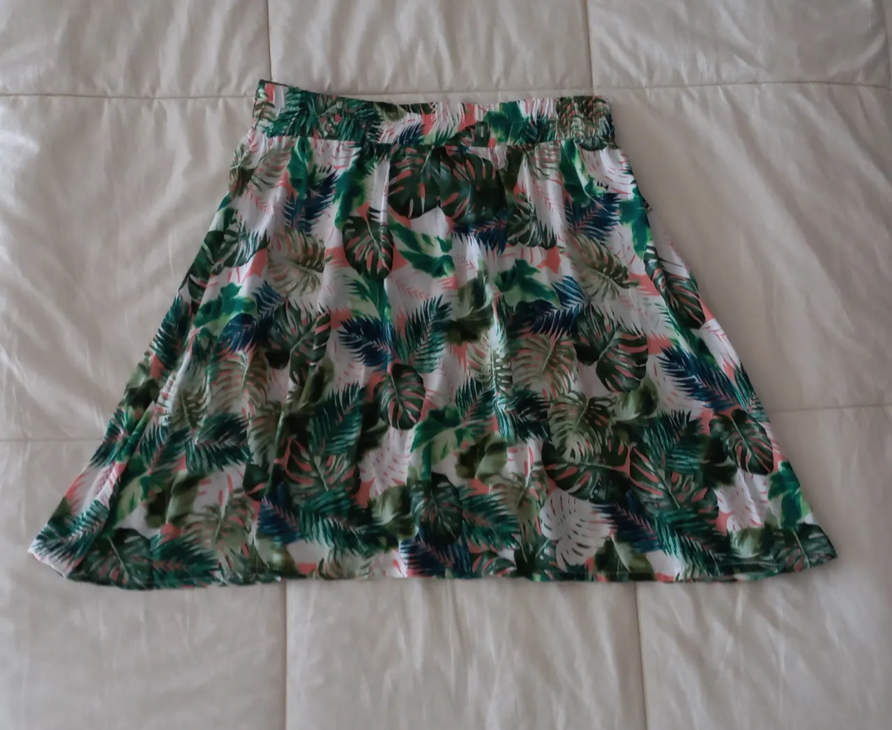 Pollera corta con estampado tropical de hojas verdes y detalles en rosa. Cintura elastizada para mayor comodidad. Ideal para un look fresco y playero.