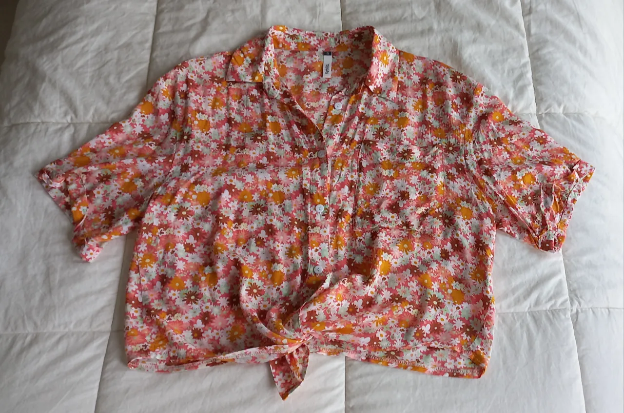 Camisa estampada con flores en tonos rosas, naranjas y blancos. Posee cuello camisero, mangas cortas y se anuda en la parte delantera. 
Super fresca
