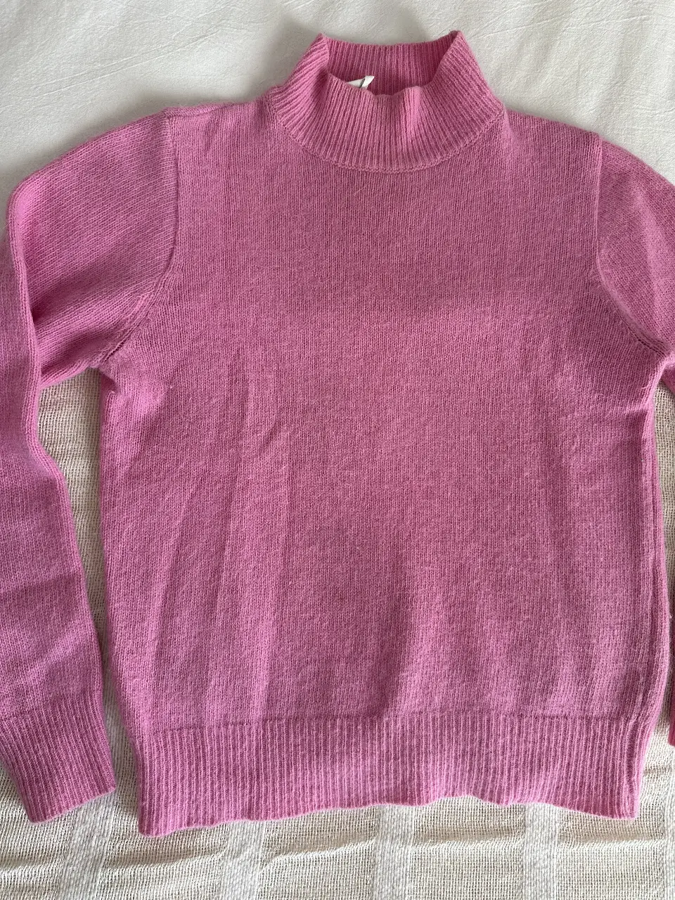 Sweater de cuello alto en color rosa, ideal para un look casual y abrigado. Perfecto para combinar con jeans o pantalones de vestir.