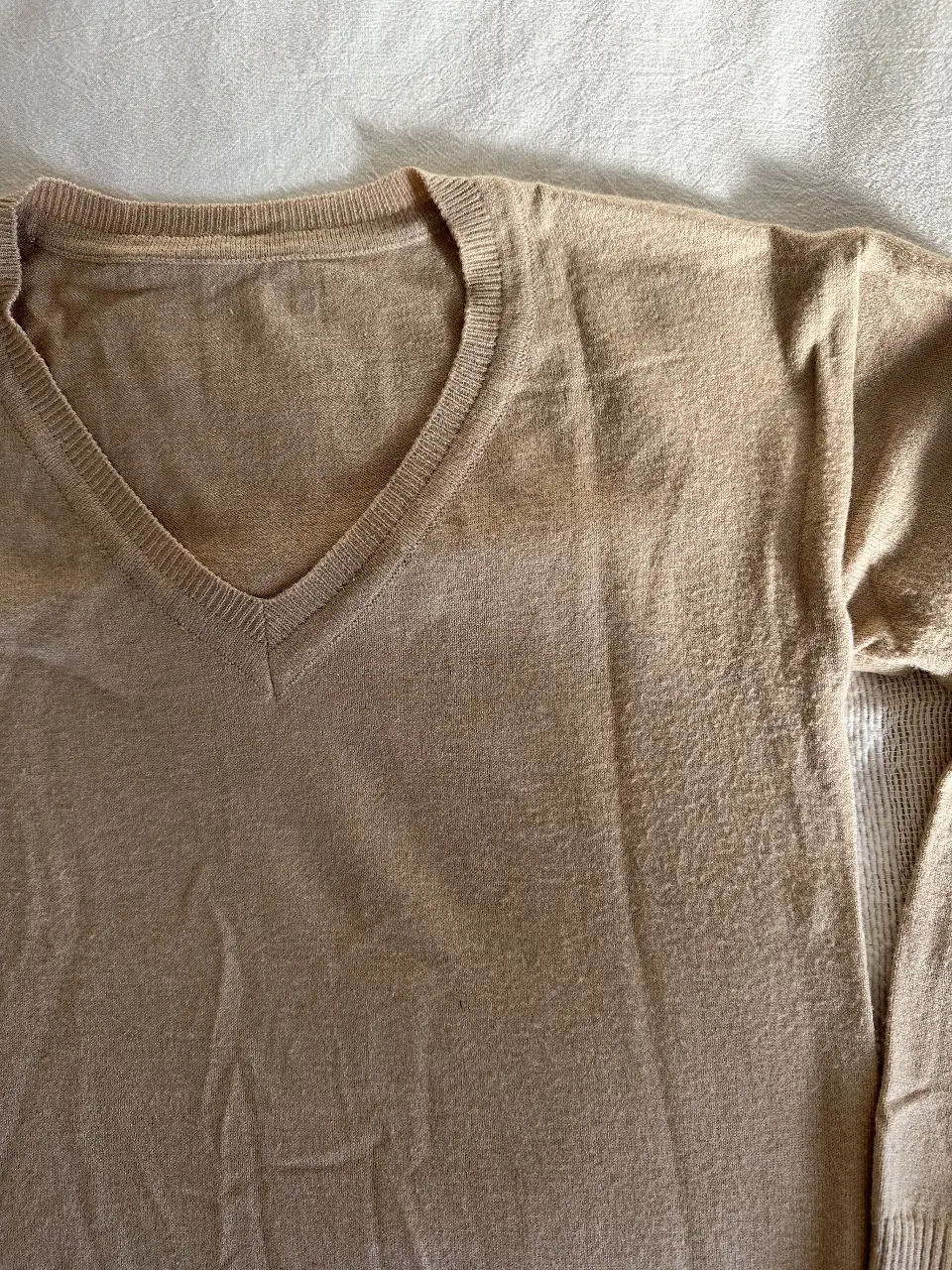 Sweater de hombre color crudo con cuello en V. Ideal para un look casual y cómodo. Perfecto para usar en otoño e invierno.
