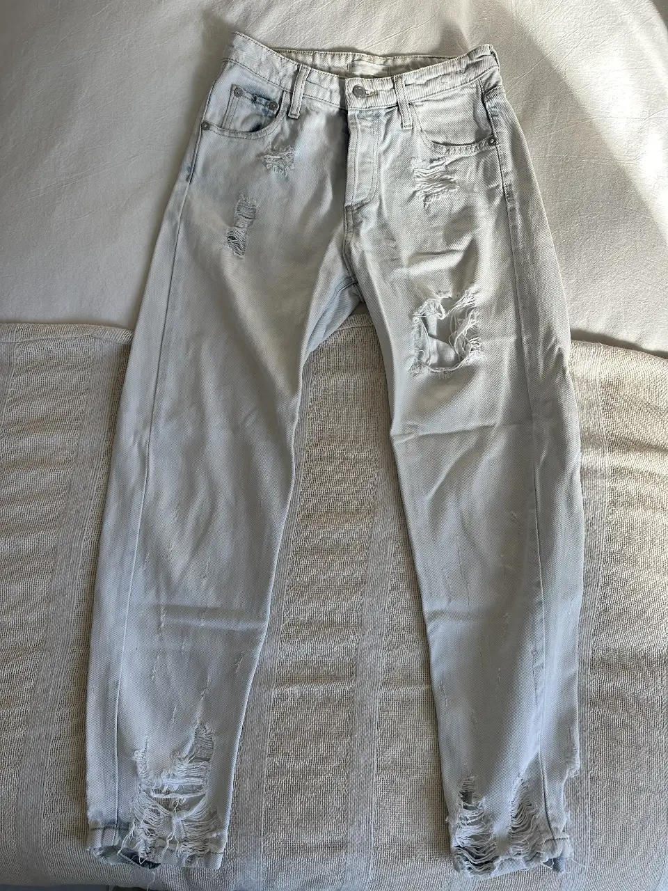 Jeans celeste claro con roturas y detalles desgastados. Tiro medio, ideal para un look casual y moderno.