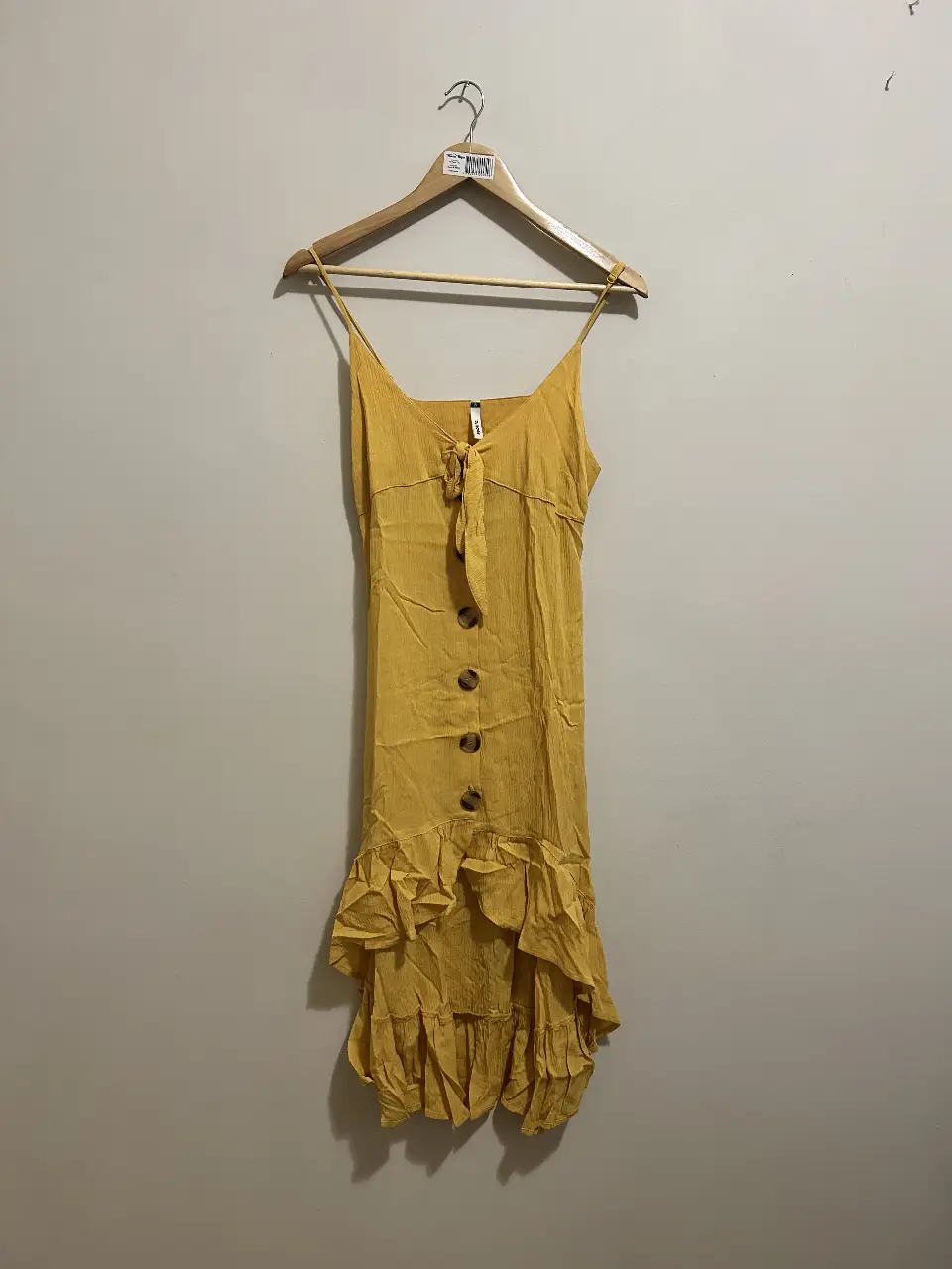 Vestido mini amarillo con tirantes finos y detalle de lazo en el pecho. Diseño con botones frontales y volados en la falda. Ideal para un look fresco y veraniego.