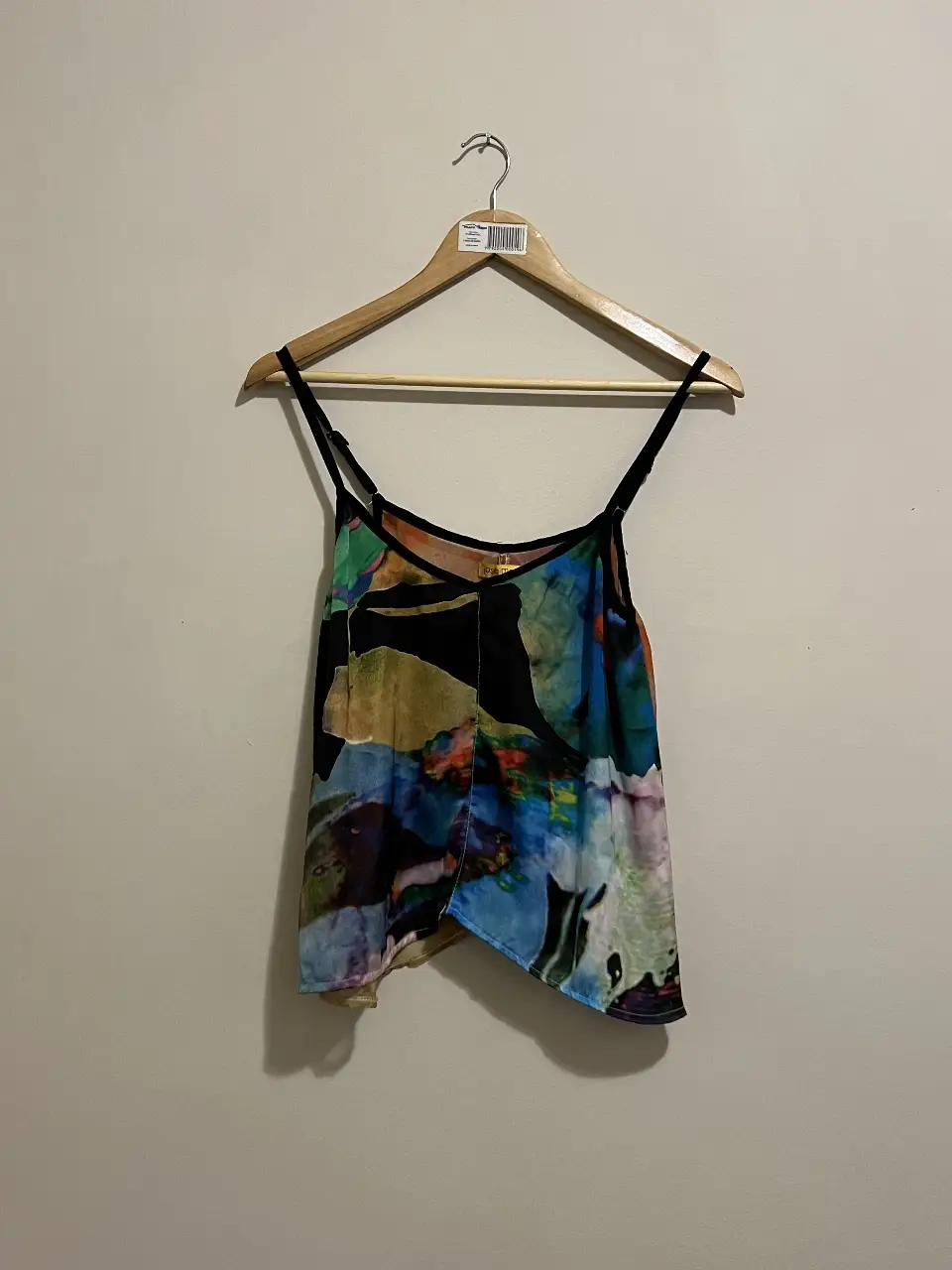 Top de mujer con estampado abstracto en tonos azules, amarillos y negros. Diseño con tirantes finos y corte asimétrico, ideal para un look fresco y moderno.