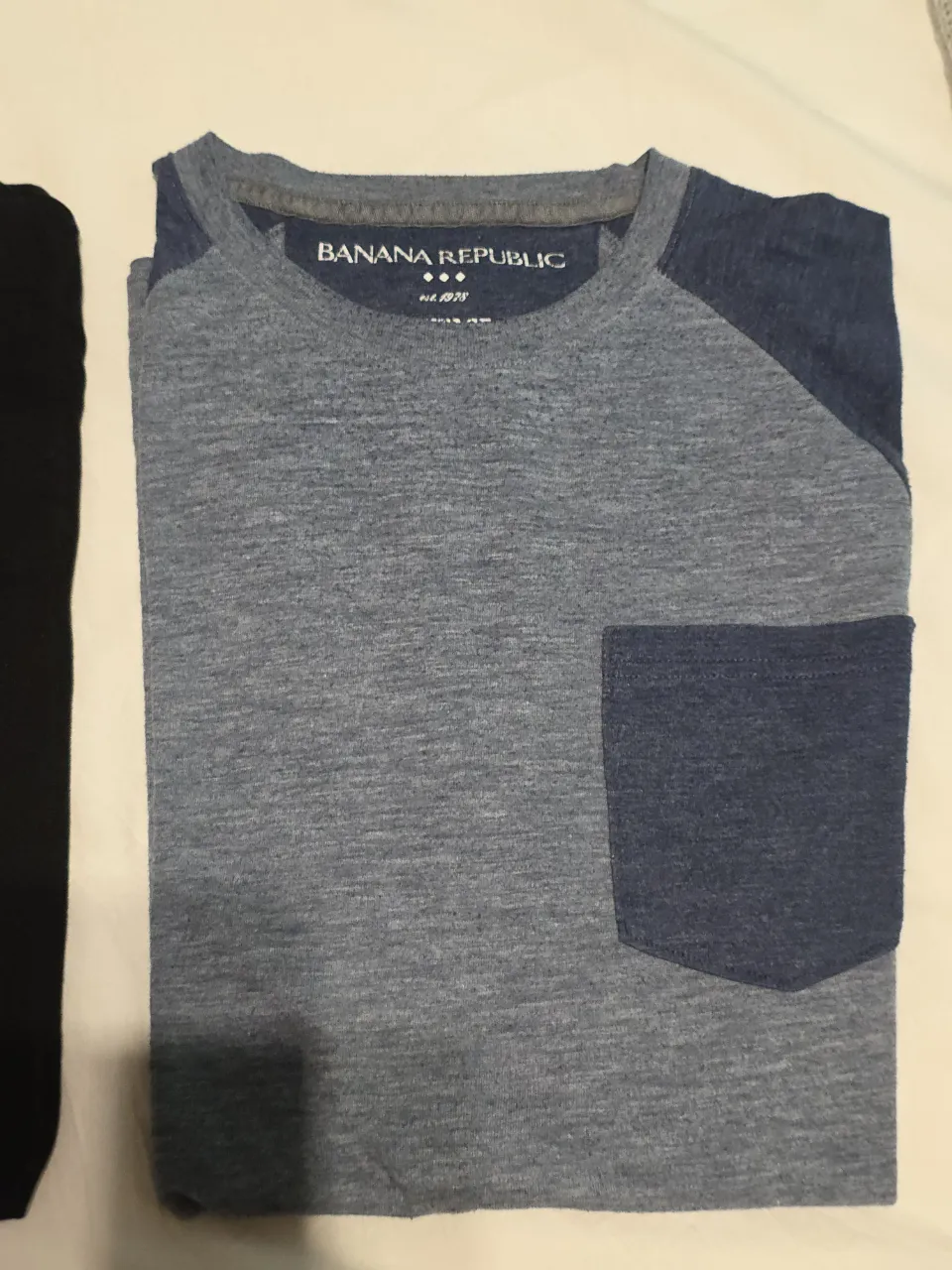Remera manga corta para hombre, de color gris con mangas y bolsillo azul. Con logo de la marca Banana Republic.