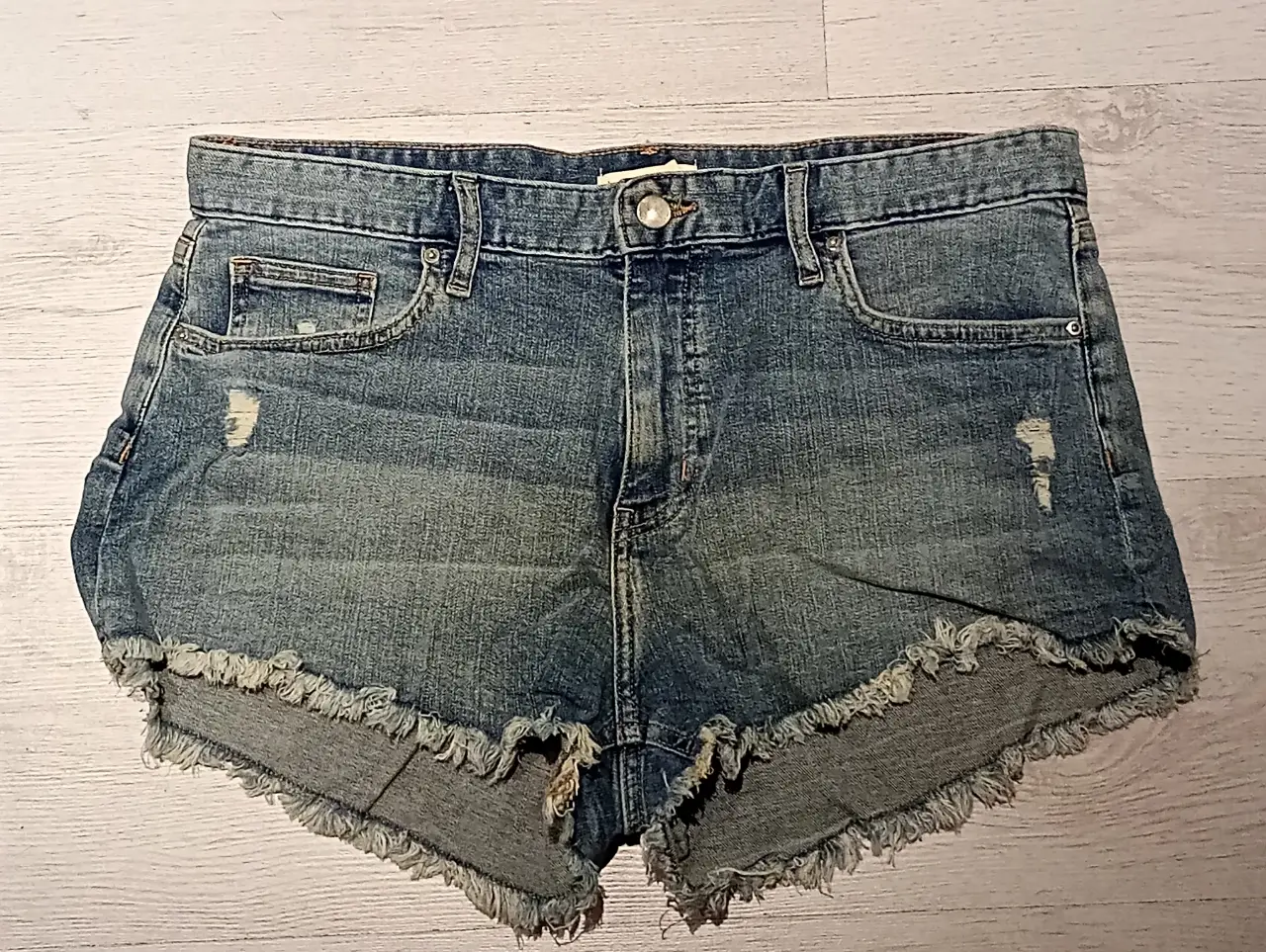 Short de jean de mujer, tiro medio, con detalles de roturas y flecos en el borde inferior. Talle 10 US / Europa 42
