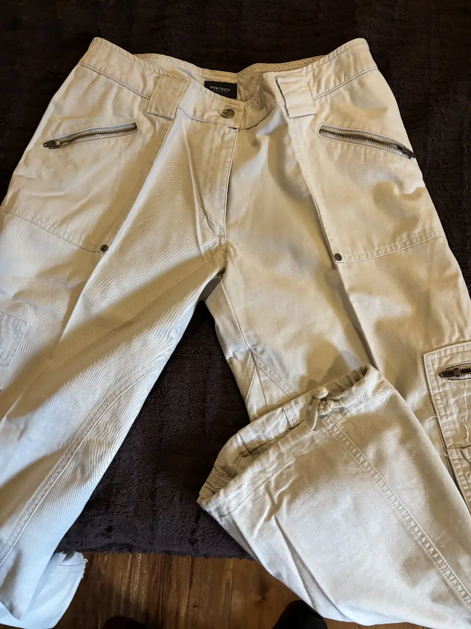 Pantalón cargo de mujer, color crudo, con múltiples bolsillos y detalles de cierre. Talle 29.