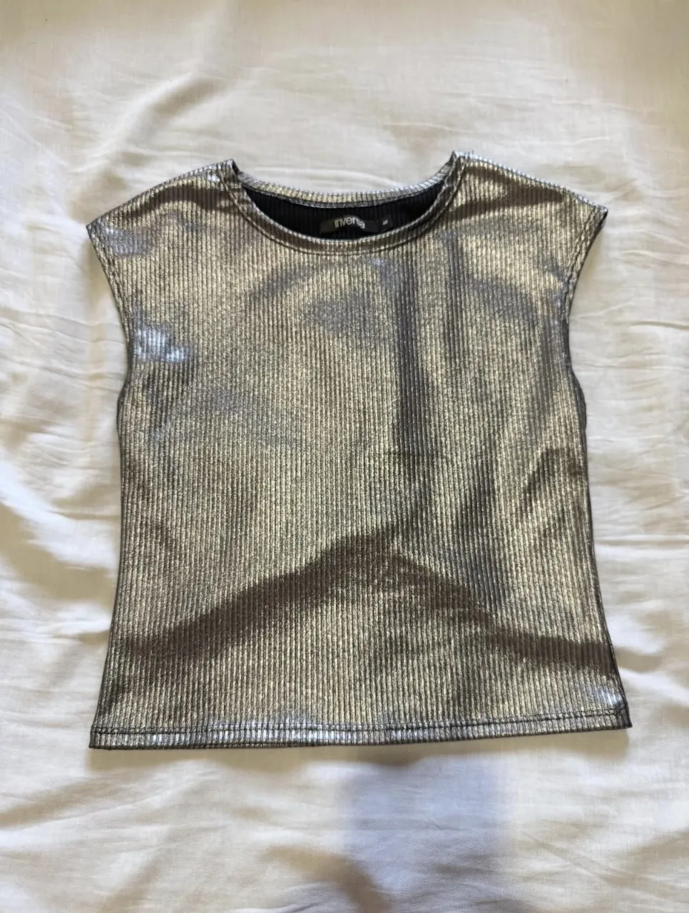 Top plateado con textura acanalada, ideal para un look moderno y llamativo. Perfecto para combinar con jeans o faldas para una salida nocturna o un evento especial.