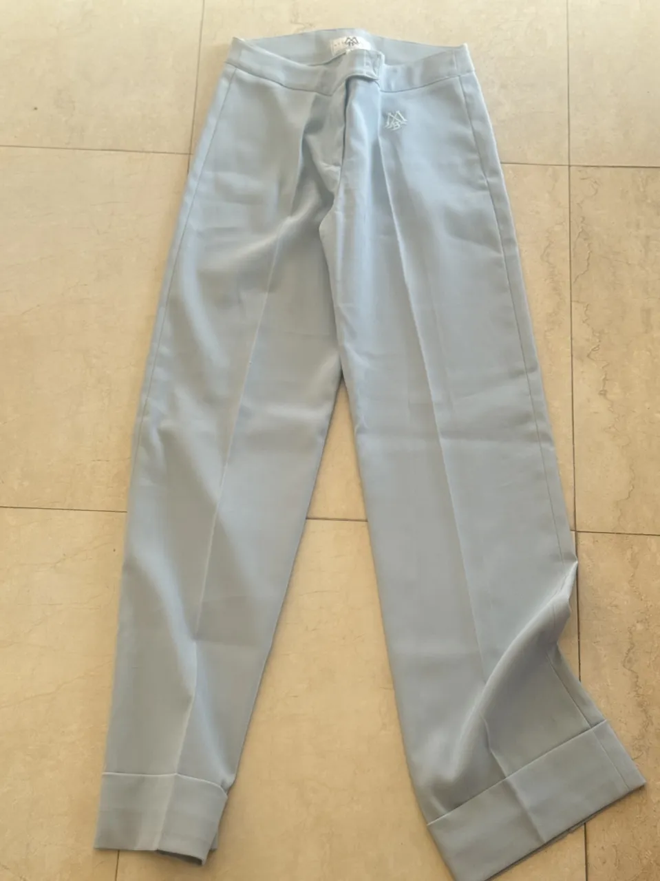 Conjunto de pantalón y blazer color celeste. El pantalón es recto con pinzas y dobladillo. El blazer tiene cuello solapa, tres botones al frente y bolsillos laterales.